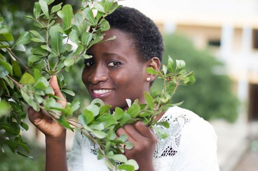 young woman hidden behind the foliage to protect against the sun.