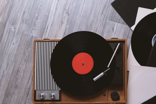 Vintage turntable with a vinyl record on gray wooden table, top view and copy space.