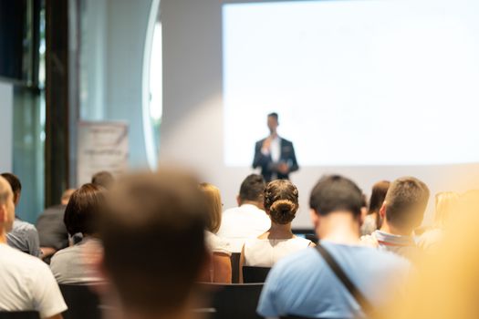 Male speaker giving a talk in conference hall at business event. Audience at the conference hall. Business and Entrepreneurship concept. Focus on unrecognizable people in audience.