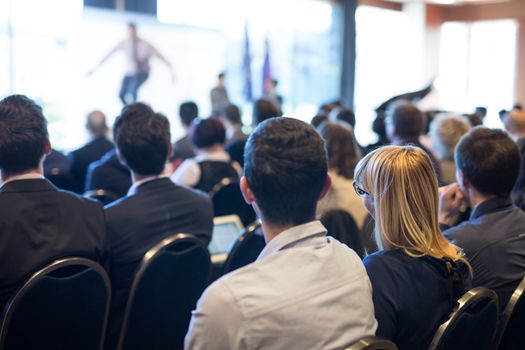 Motivational speaker giving a talk in conference hall at business event. Audience at the conference hall. Business and Entrepreneurship concept. Focus on unrecognizable people in audience.