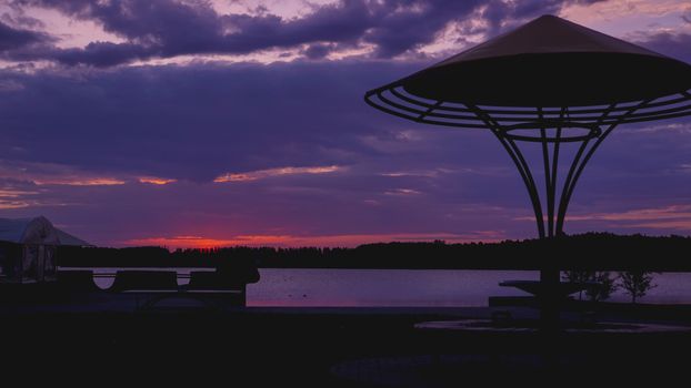 Beach umbrellas against a red-violet sunset by the sea