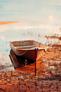 Little row boat in the shallows with reflections in late afternoon light