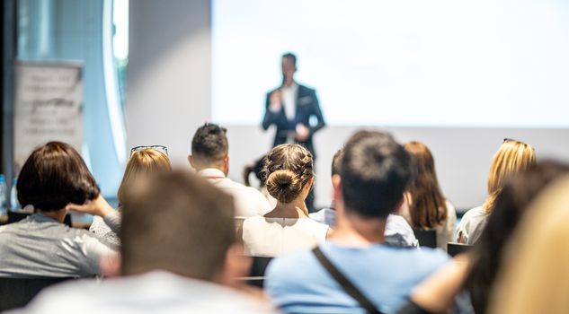 Male speaker giving a talk in conference hall at business event. Audience at the conference hall. Business and Entrepreneurship concept. Focus on unrecognizable people in audience.