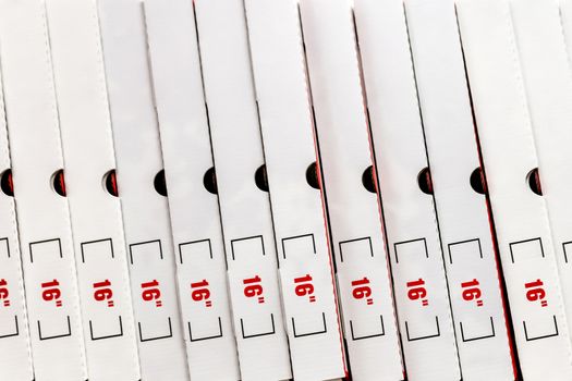 A large stack of white pizza boxes with red numbers diaimeter 16