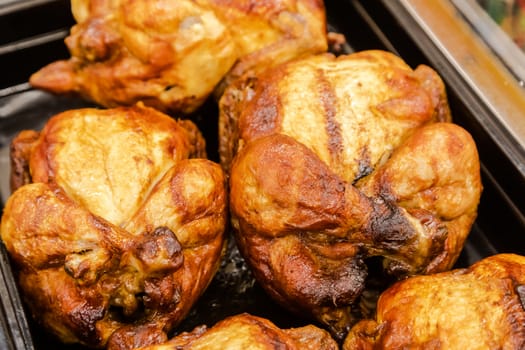 Several whole carcasses of roast chicken a grill on a tray