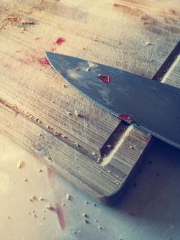 blade knife lying on a dirty wooden board. knife stained with slicing ingredients for dinner