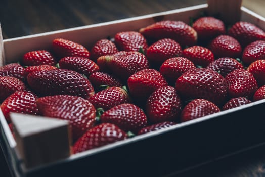 strawberries in a wooden box on a wooden table, healthy sweet food, vitamins and fruity concept. Food frame background