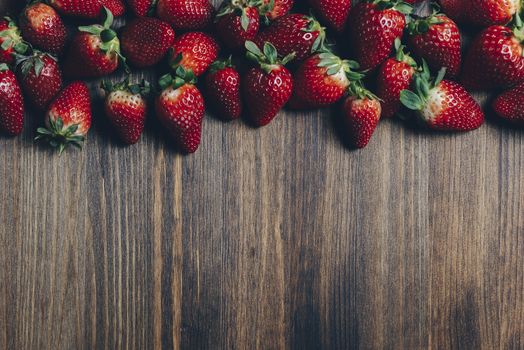 Fresh and juicy strawberries on wooden background in rustic style, healthy sweet food, vitamins and fruity concept. Top view, copy space for text
