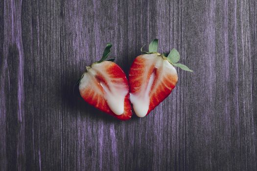 metaphor of sex with strawberries and milk on a purple wooden background. Vagina and semen symbol, sex concept. Top view, copy space for text
