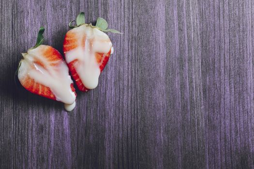 metaphor of sex with strawberries and milk on a purple wooden table. Vagina and semen symbol, sex concept. Top view, copy space for text