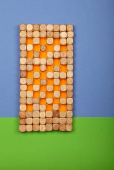 Close up wooden toy building blocks in shape of high rise tower house over green and blue color paper background for grass and sky with copy space