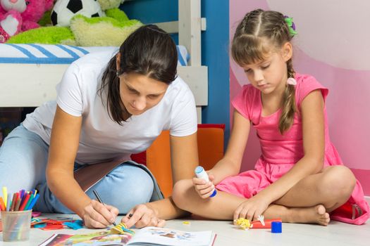 Mom and daughter sitting on the floor in the nursery and crafting crafts