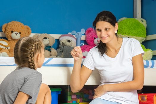 Mom shows her daughter a homemade figurine on her finger