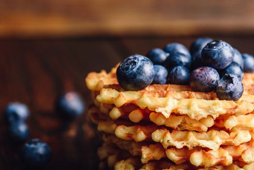 Blueberries on the Top of the Waffles Stack and Other Scattered on Wooden Background.