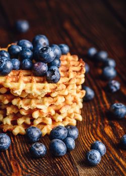 Blueberries on the Top of the Belgian Waffles Stack and Other Scattered on Wooden Background. Copy Space on the Left.