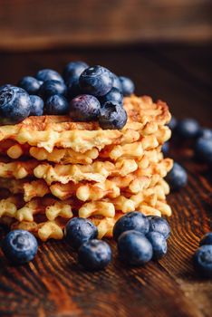 Blueberries on the Top of the Waffles Stack and Other Scattered on Wooden Background.