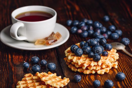 Cup of Tea with Blueberries and Belgian Waffles Stack on Wooden Background.