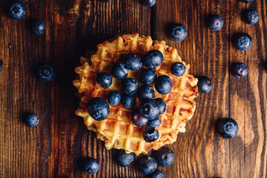 Blueberries on the Top of the Waffle and Other Scattered on Wooden Background.
