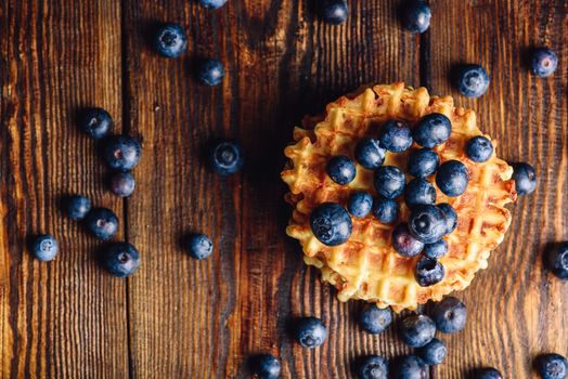Blueberries on the Top of the Waffle and Other Scattered on Wooden Background. Copy Space on the Left.