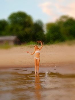 Summer holidays, vacation and beach concept - blonde girl in white bikini posing on the beach. Background blur.