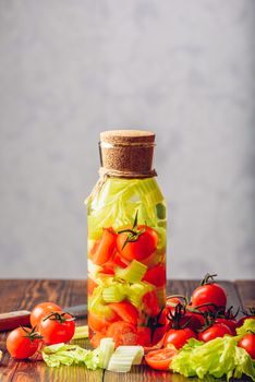 Vegetable Detox Beverage with Sliced Clery Stems and Cherry Tomato with Ingredients on Wooden Table. Vertical Orientation and Copy Space.