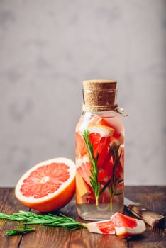 Cleansing Water Infused with Sliced Raw Grapefruit and Fresh Springs of Rosemary. Vertical Orientation. Copy Space on the Top.