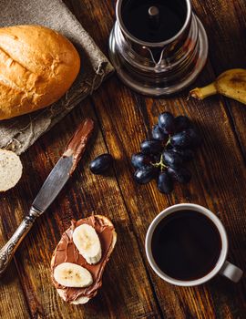 Breakfast with Banana Sandwich with Chocolate Spread, Coffee Cup and Grapes. Vertical Orientation and View from Above.