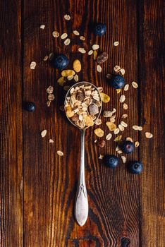 Spoonful of Granola and Blueberry on Wooden Table. View from Above. Vertical Orientation.