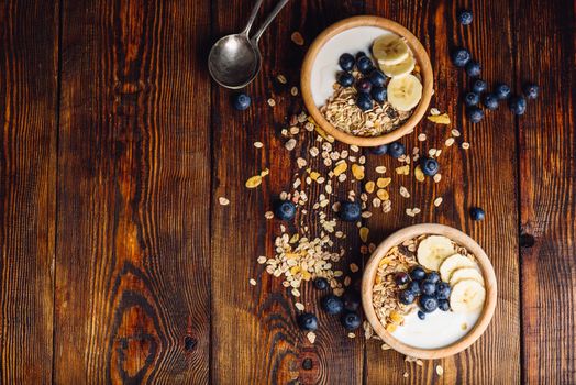 Healthy Breakfast with Granola, Banana, Blueberry and Greek Yoghurt. Scattered Ingredients on Wooden Table. View from Above and Copy Space.