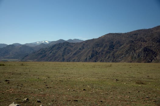 A picturesque fertile valley surrounded by mountains stretching beyond the horizon. Altai, Siberia, Russia.