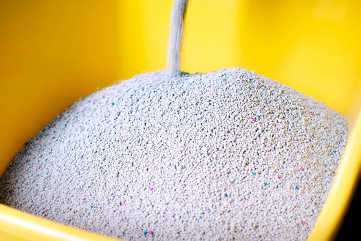 Fresh Cat Sand Pouring into a Yellow Litter Box