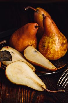 Few Golden Pears on Wooden Table with Sliced One, Fork and Knife.Vertical Orientation.