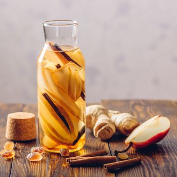 Bottle of Water Infused with Sliced Pear, Cinnamon Stick, Ginger Root and Dark Sugar. Copy Space.