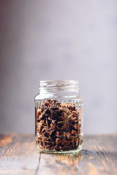 Jar of Star Anise Fruits and Seeds on Wooden Table. Vertical Orientation with Copy Space.