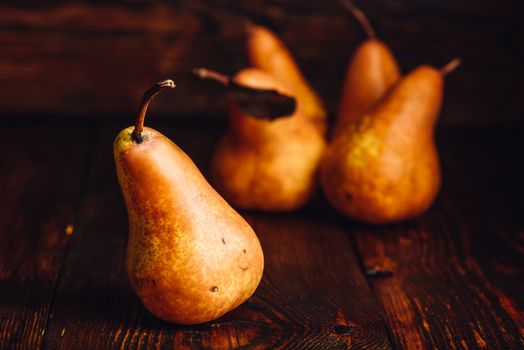 Golden Pear on Wooden Table and Few Pears on Backdrop.