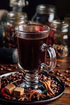 Cup of Coffee on Metal Plate with Beans, Refined Sugar and Cinnamon Stick, Anise and Chili Pepper.