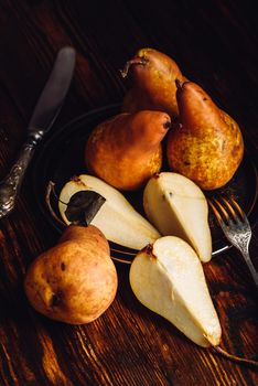 Few Golden Pears on Wooden Table with Sliced One, Fork and Knife.Vertical Orientation.