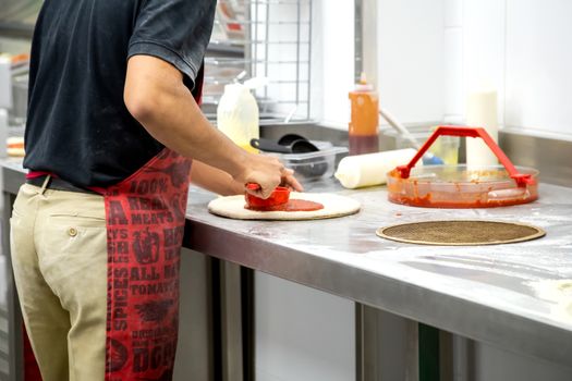 Cooking dough by the hands of men in a pizza restaurant