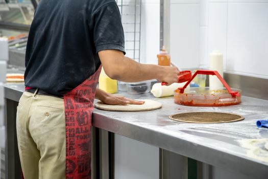 Cooking dough by the hands of men in a pizza restaurant