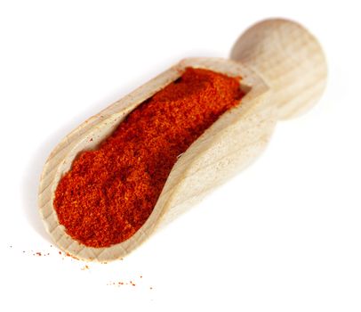 Red pepper ground. Spice powder on wooden spoon, isolated over White Background.