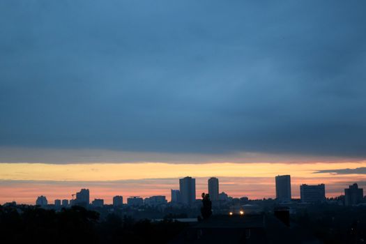 sunset over city, round red sun and the night sky