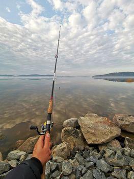 Fishing on the lake in morning, view on hand holding fishing rod