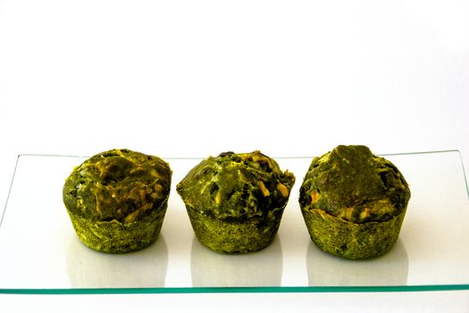 three green cakes on a glass tray and  white background