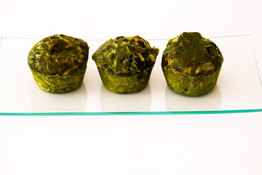 three green cakes on a glass tray with white background
