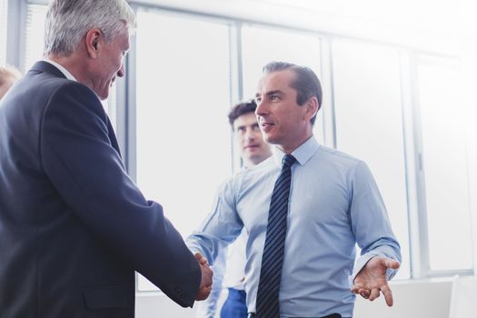 Happy business shaking hands in modern office