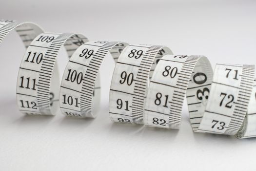 An image of a rolled tape measure on a white background