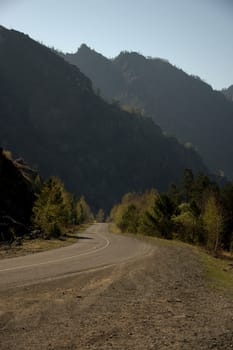 A winding dirt road winding at the foot of the high mountains. Altai, Siberia, Russia.