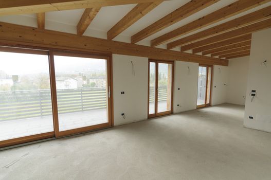 Building site or home renovation in progress: empty open space with large windows and exposed wooden beams