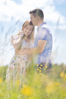 Young happy pregnant couple hugging in nature. Concept of love, relationship, care, marriage, family creation, pregnancy, parenting