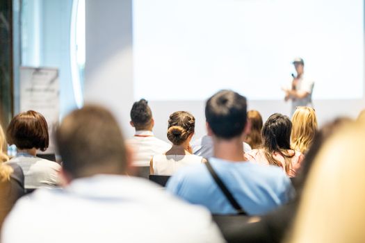 Male speaker giving a talk in conference hall at business event. Audience at the conference hall. Business and Entrepreneurship concept. Focus on unrecognizable people in audience.